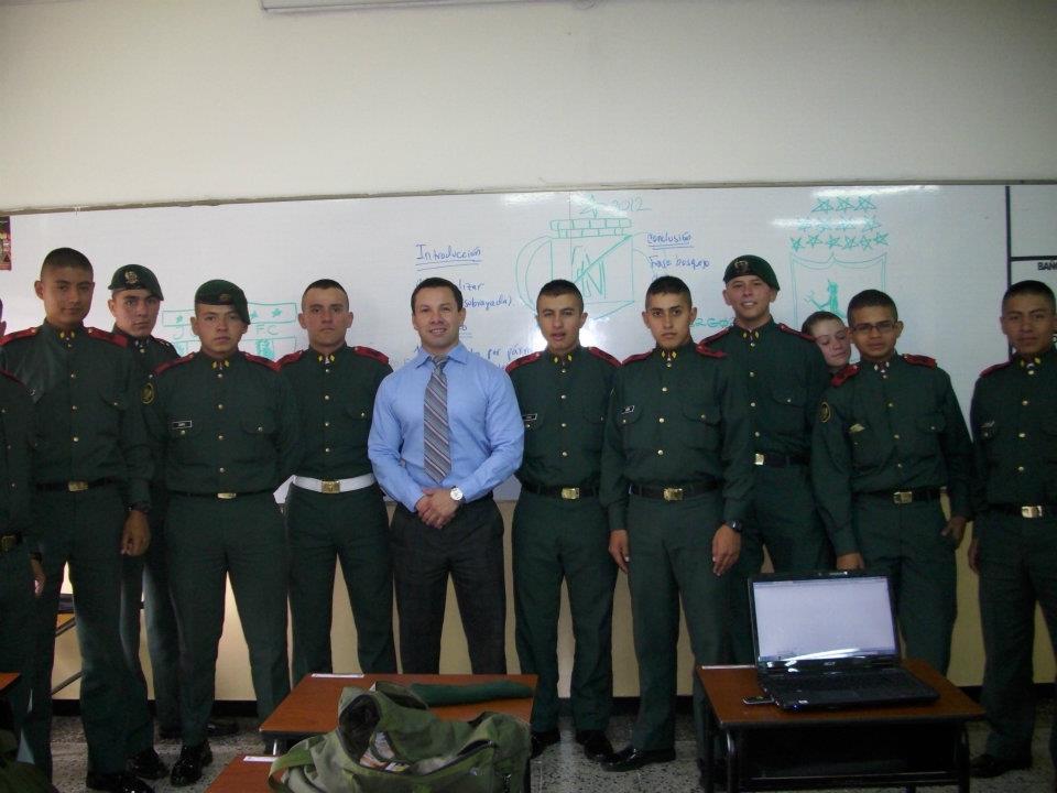 John standing with a group of uniformed students in a classroom.